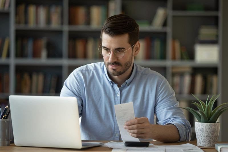 Accountant man employee sit at a desk using laptop app make payments online