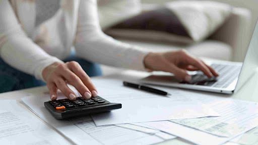 remote bookkeeping business - Woman working with a calculator and laptop