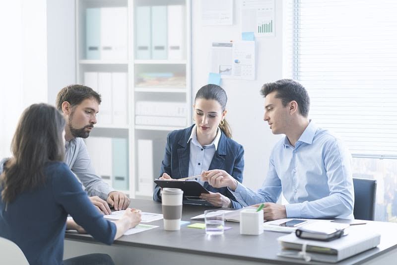 four individuals in a conference room having a meeting