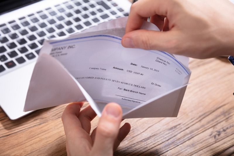 closeup shot of an employee opening an envelope with their paycheck inside