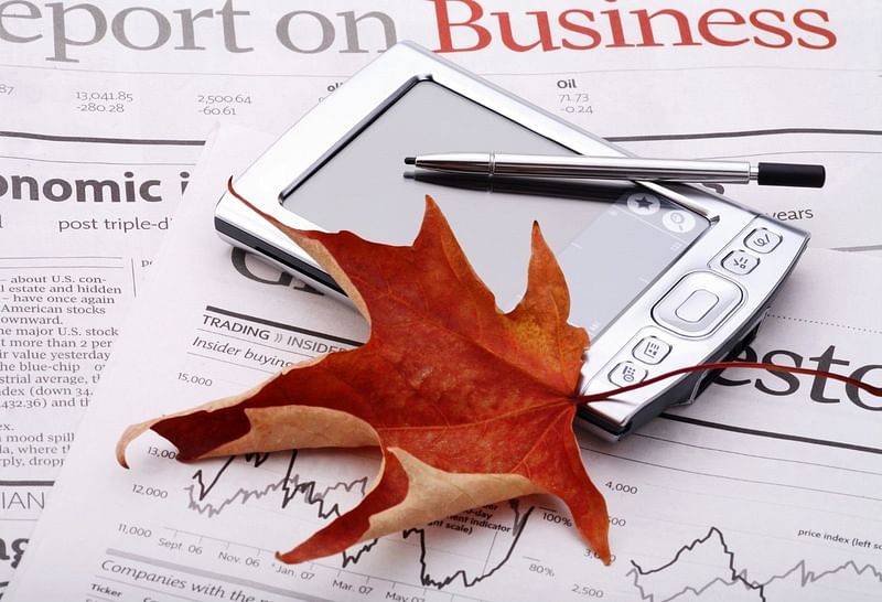 a maple leaf and notepad on top of a newspaper with the headline saying "Report on Business"