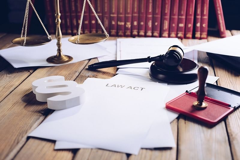 a printed law act with a stamp, a gavel, sound blocker, a weighing scale, and some law books