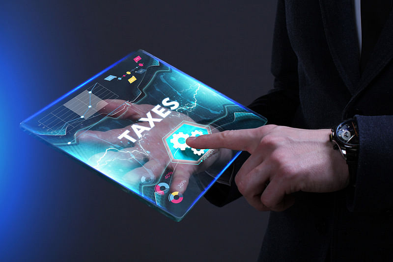 a man holding a tab-like device clicking the "Taxes" text projected on the screen